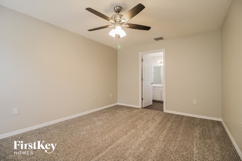 the spacious living room with ceiling fan and carpet