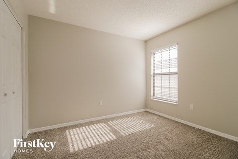 a bedroom with a window and a carpeted floor