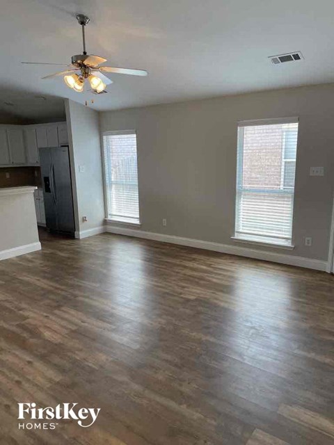 an empty living room with wood floors and a ceiling fan