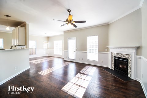 A spacious living room with a fireplace and a ceiling fan.