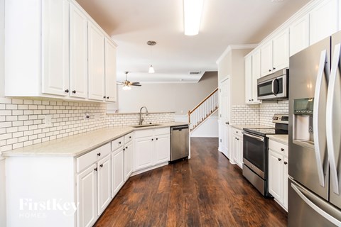 A kitchen with white cabinets and a wooden floor.
