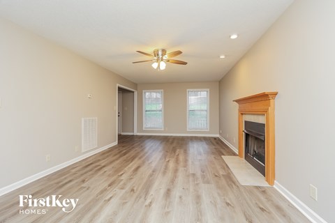 A spacious room with a fireplace and a ceiling fan.