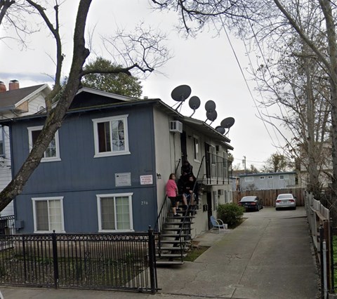 A blue building with a black fence and satellite dishes on the roof.
