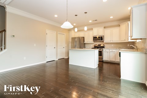 A kitchen with white cabinets and a wooden floor.