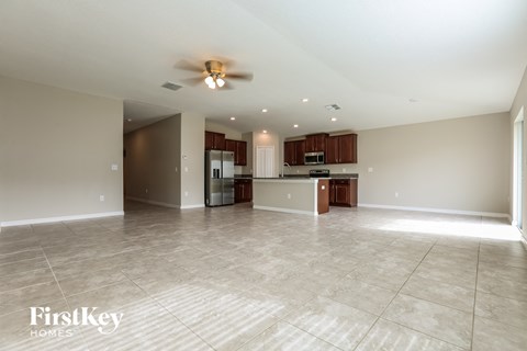 an empty living room and kitchen with a ceiling fan