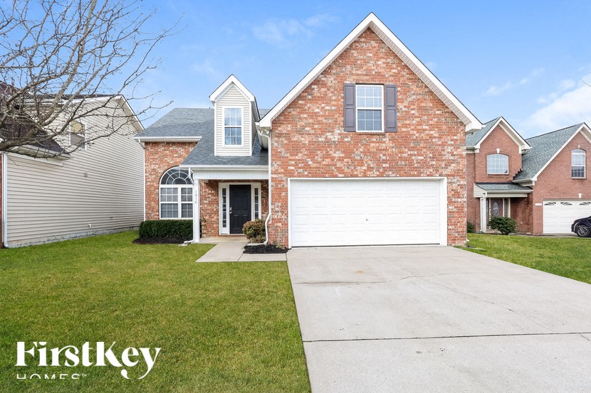 A brick house with a garage door is for sale.