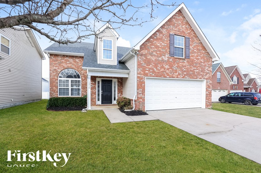 A brick house with a garage and a tree in front.