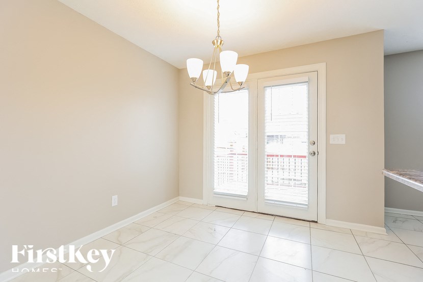 A room with a chandelier and a door leading to a balcony.