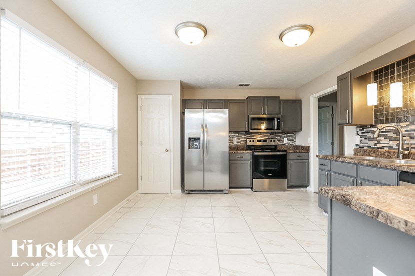A kitchen with a refrigerator, microwave, oven, and sink.