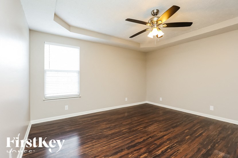 A room with a ceiling fan and wooden flooring.