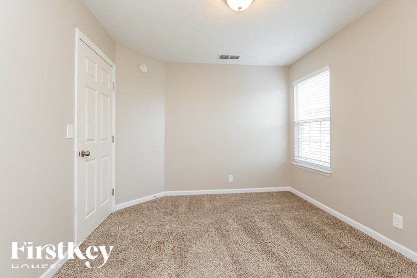 A carpeted room with a door and a window.
