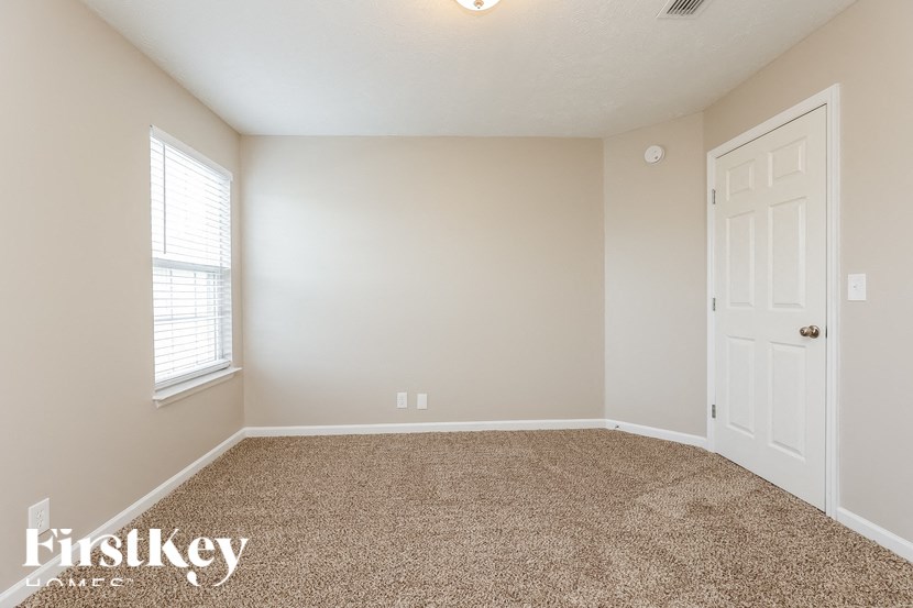 A room with a carpeted floor, a door, and a window.