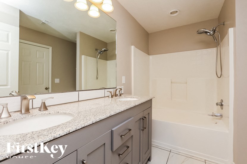A bathroom with a double sink vanity and a shower.