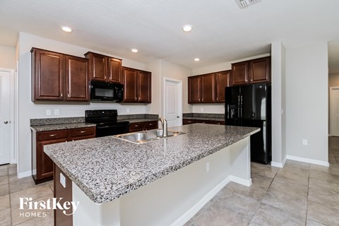 a kitchen with granite counter tops and dark wood cabinets