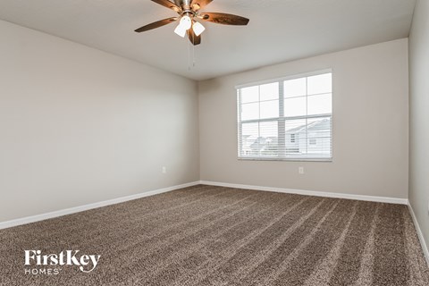 the spacious living room with ceiling fan and carpet