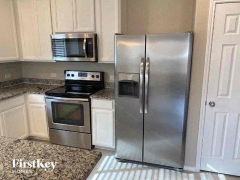 A kitchen with a stainless steel refrigerator and microwave above an oven.