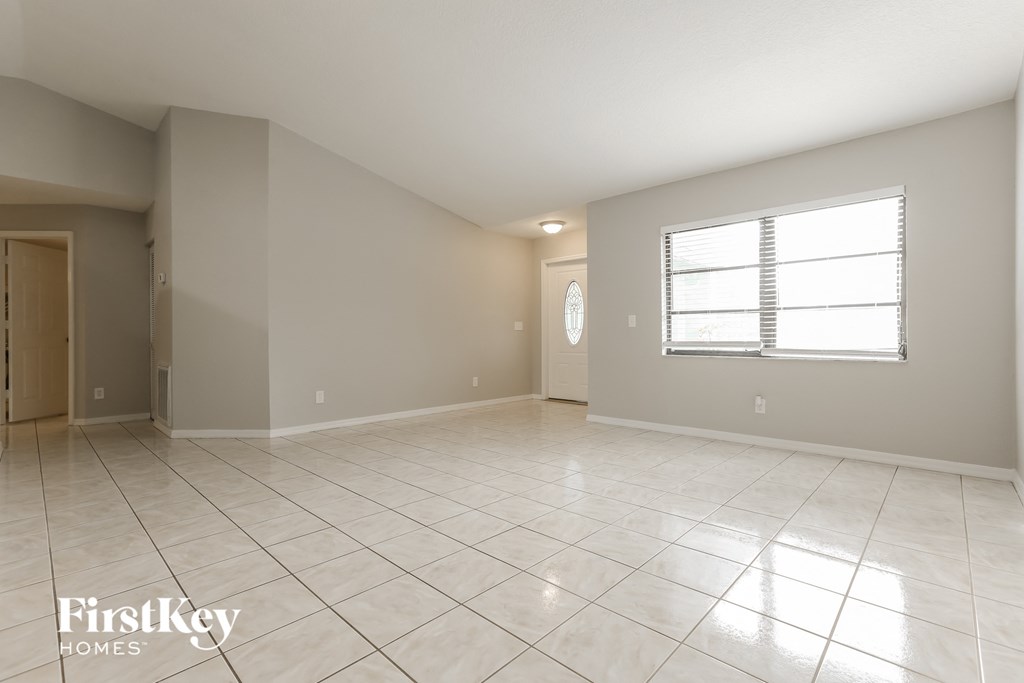 the spacious living room with tiled floors and a window