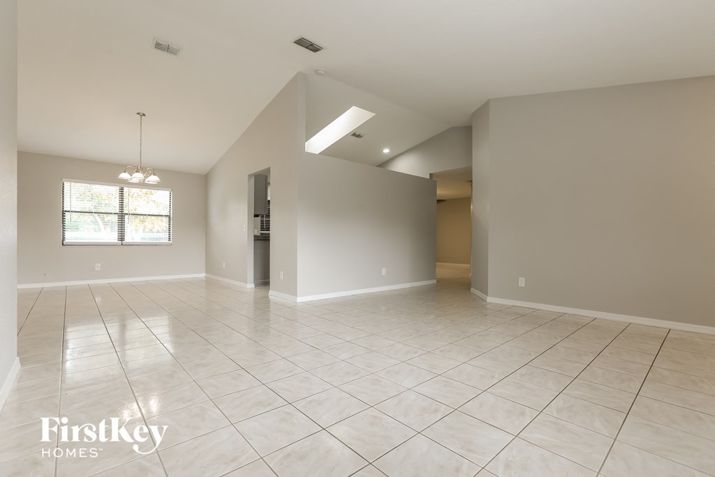 a large empty living room with tile flooring and grey walls