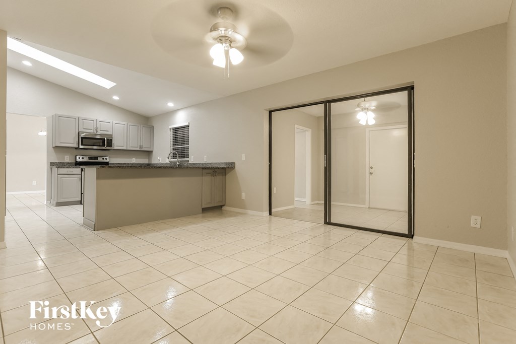 an empty living room with a kitchen and a glass sliding door