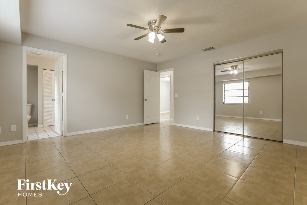 an empty living room with a ceiling fan and tiled floors