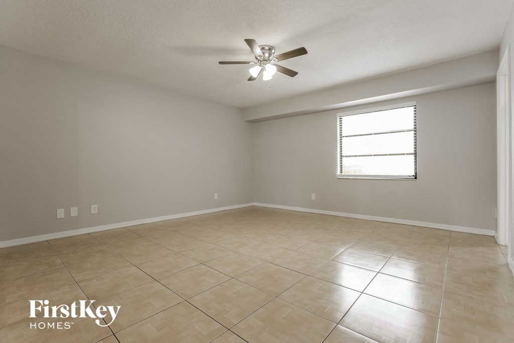 an empty living room with a ceiling fan and tiled floor