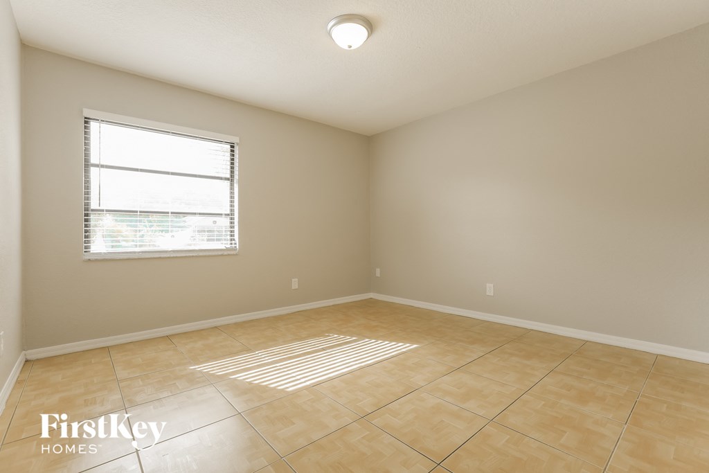 the spacious living room with tiled floors and a window