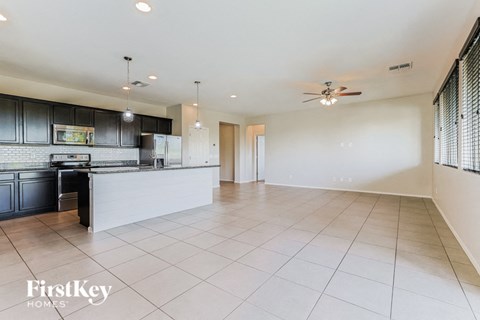 an empty kitchen and living room with white tile floors and black cabinets