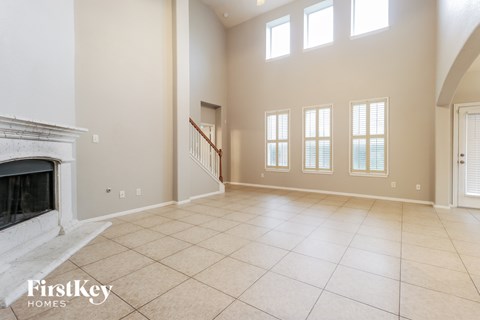 A spacious living room with a fireplace and a staircase.