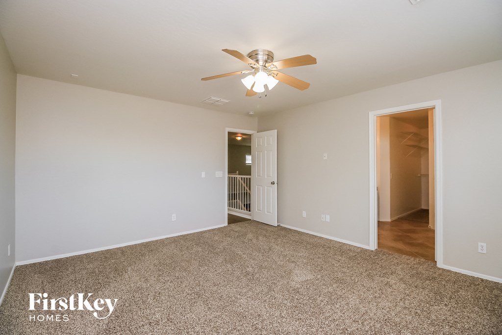 a spacious living room with carpet and a ceiling fan