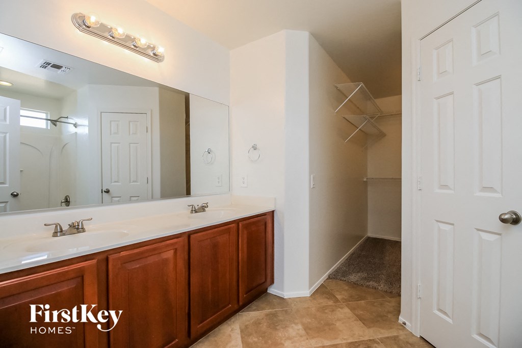 the master bathroom has a large mirror and a double sink