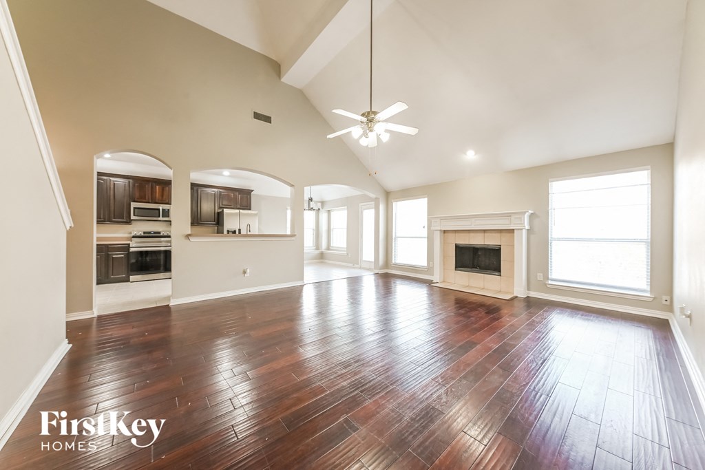 A spacious living room with wood flooring and a fireplace.