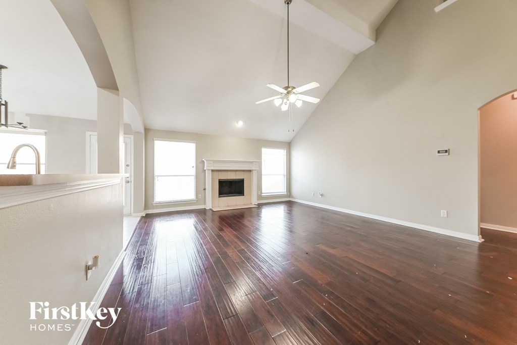 A spacious room with wooden floors and a fireplace.