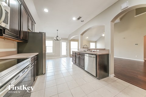 A modern kitchen with a stainless steel dishwasher and a white tiled floor.