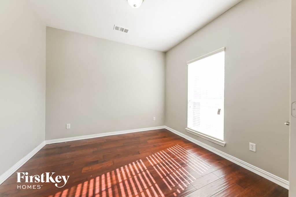 A room with wooden flooring and a window letting in light.