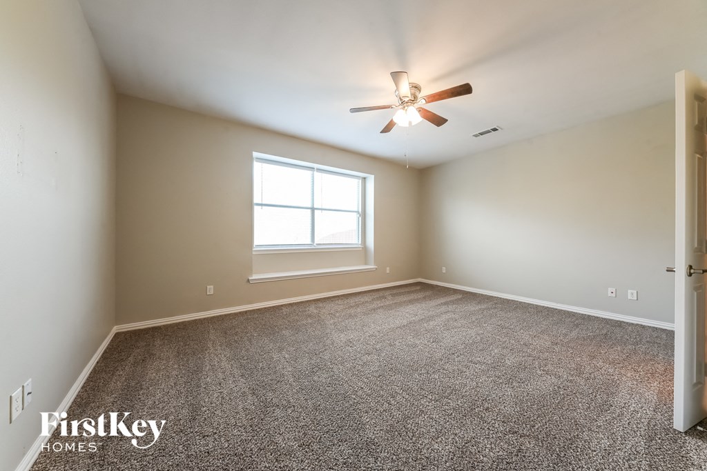 A spacious room with a ceiling fan and a window.