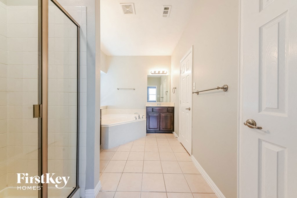 A white hallway with a glass door leading to a bathroom.