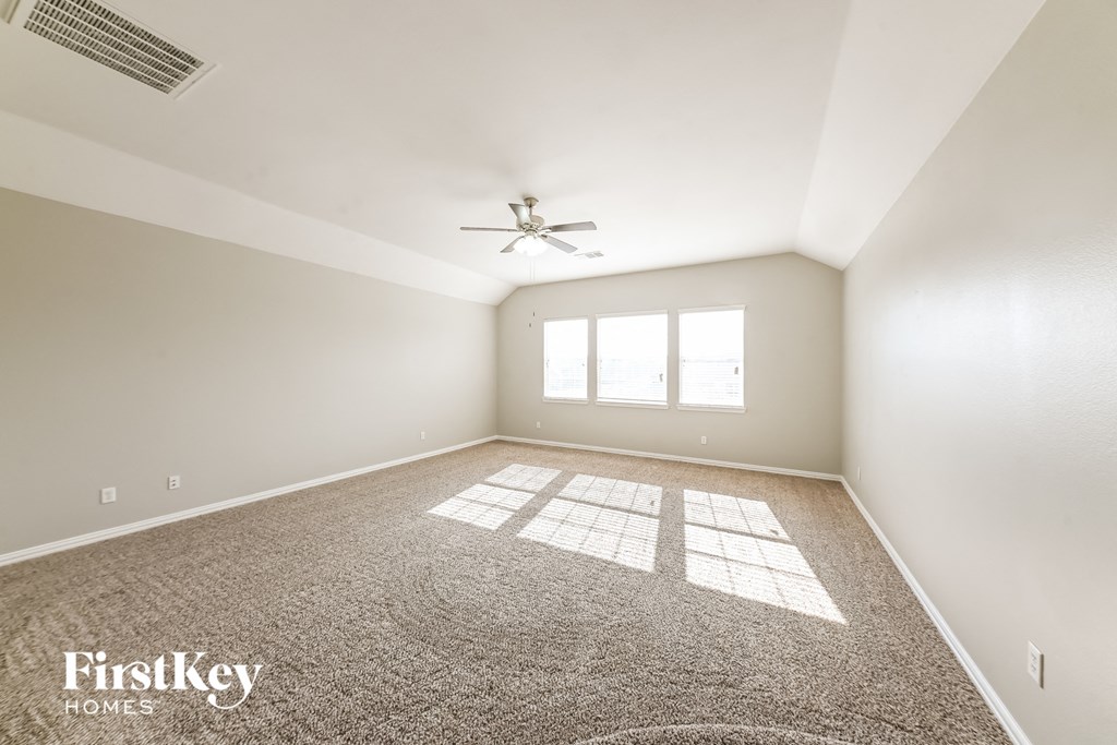 A spacious room with a carpeted floor and a ceiling fan.