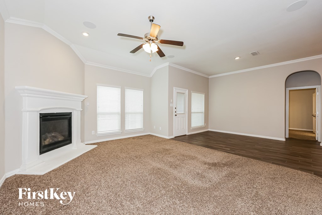 A spacious room with a fireplace and a ceiling fan.