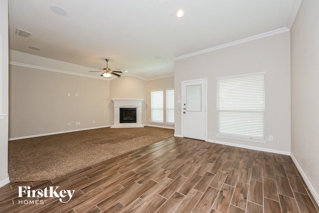 A spacious living room with wood flooring and a fireplace.