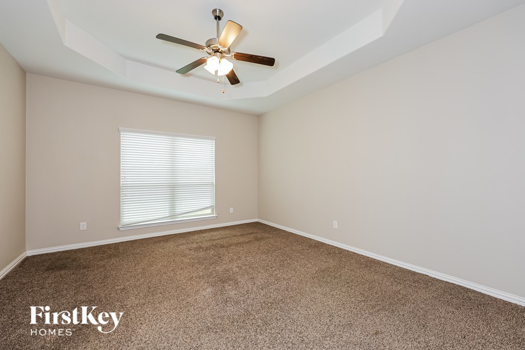 A room with a carpeted floor and a ceiling fan.