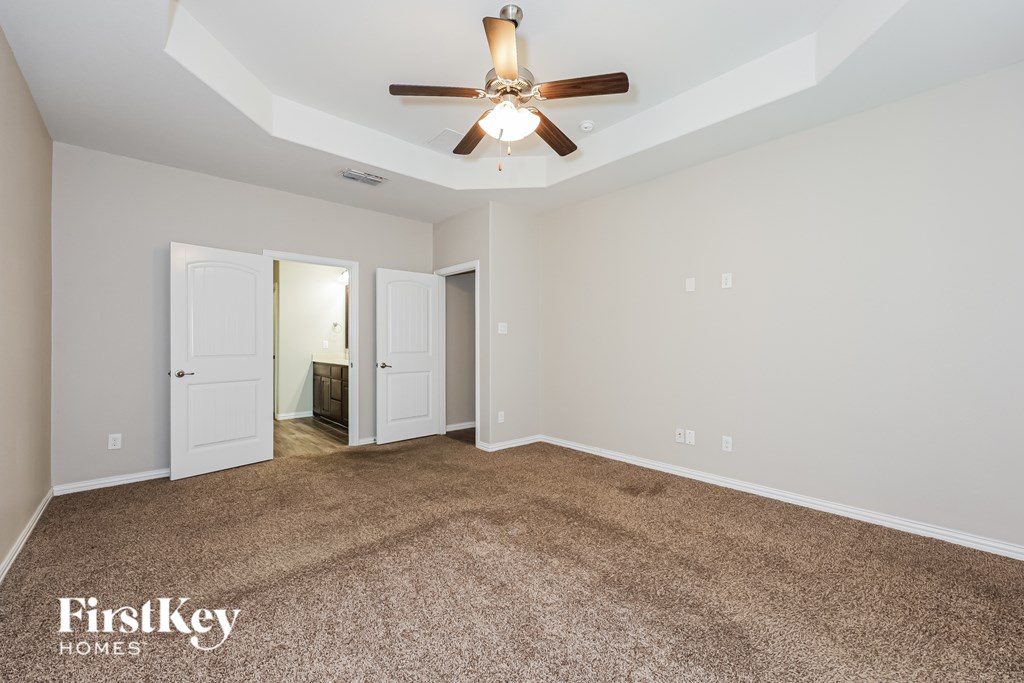 A room with a carpeted floor and a ceiling fan.