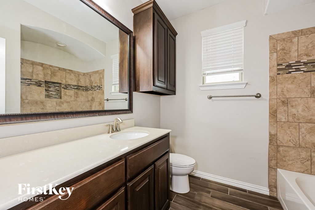 A bathroom with a white sink and brown cabinets.