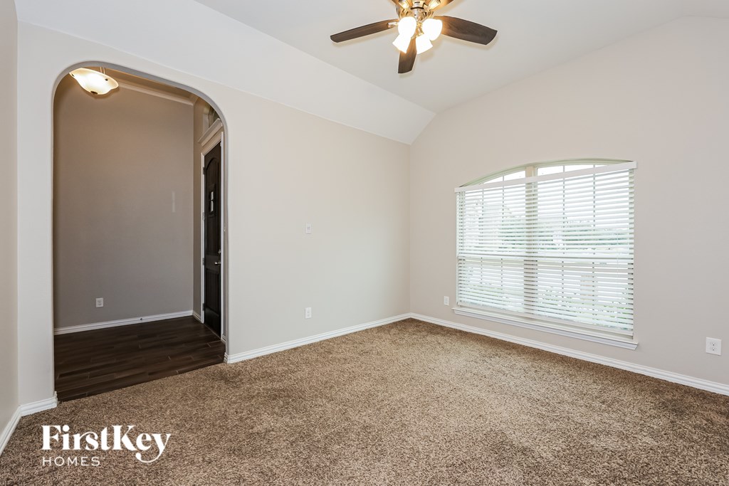 A spacious room with a carpeted floor and a ceiling fan.