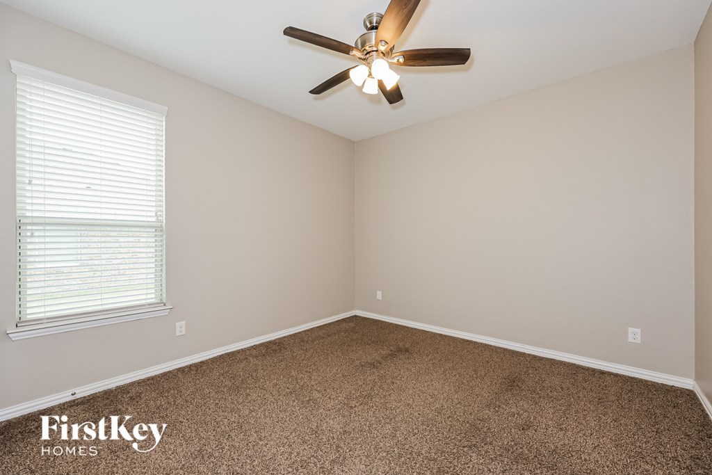 A room with a ceiling fan and a window with blinds.