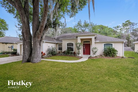 a white house with a red door and a tree