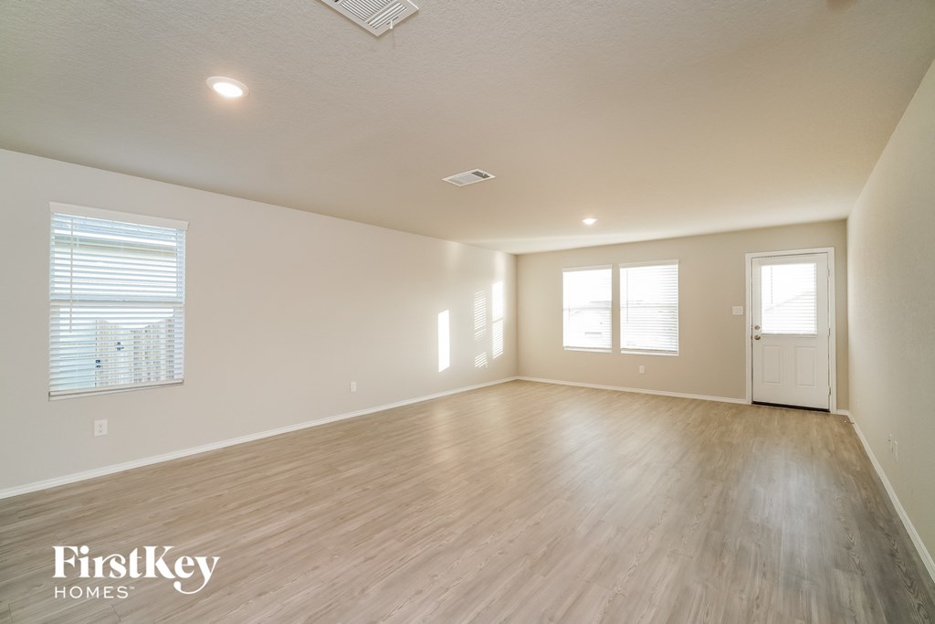 the spacious living room with wood flooring and white walls
