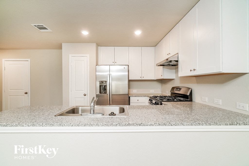 a kitchen with white cabinets and a sink and a refrigerator