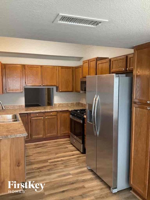 A kitchen with wooden cabinets and a stainless steel refrigerator.
