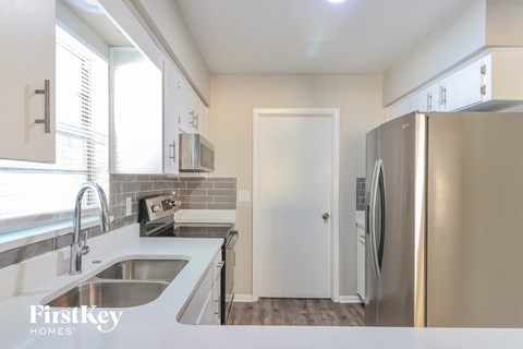 A kitchen with a stainless steel refrigerator and a white sink.