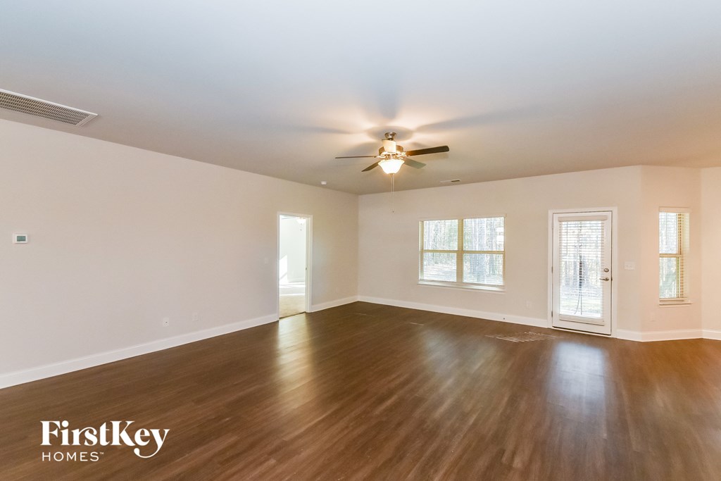 A spacious room with wooden floors and a ceiling fan.